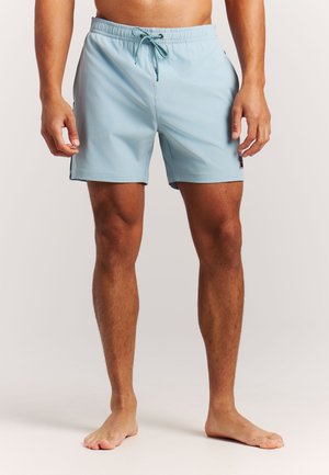 Shorts de bain bleu clair avec une ceinture élastique et un cordon de serrage. Fabriqués en tissu lisse avec des poches latérales et une petite étiquette logo.