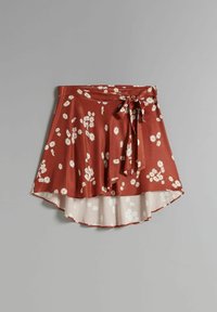 Gonna floreale rossa in tessuto leggero, orlo asimmetrico, cintura da annodare e motivi di margherite bianche sul davanti.