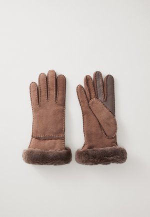 Brune semskede hansker med en myk pelsmansjett, med fingerdesign og en litt mørkere brun lapp på høyrehansken for ekstra tekstur.