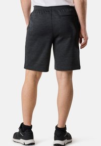 Mörkgrå sportshorts med texturerat tyg, elastisk midja och en bakficka, parat med svarta sportskor.
