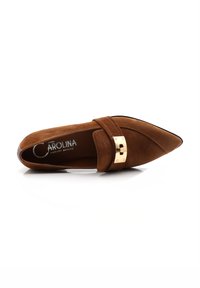 Bruine suède ballerina met spitse neus, gouden hardware-accent en een decoratieve band. Gladde textuur met een instapontwerp.