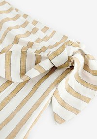 Tissu rayé avec des lignes dorées et crème alternées, doté d'un détail en nœud. Texture douce avec un aspect tissé et une finition lisse.