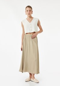 Vit linne kort topp med framknappar, tillsammans med en svängande beige kjol och beige slip-on skor. Enkelt mönster, löst snitt och mjuk textur.