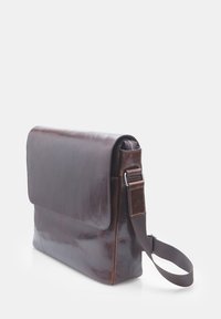 Brown leather messenger bag with a flap closure, adjustable strap, and smooth texture. Features a zip pocket on the side.