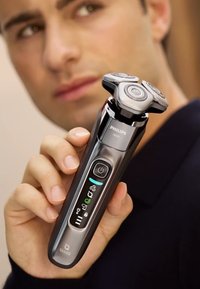 Philips elektrische scheerapparaat, met een slank zwart lichaam met zilveren accenten, een driekops scheersysteem en een LED-display met iconen.