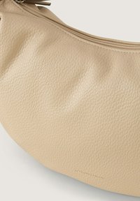 Borsa a tracolla in pelle beige con finitura testurizzata, dotata di zip superiore e forma tondeggiante. Logo discreto sulla superficie.