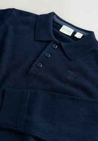 Granatowy sweter w polo z dzianiny z krótkim kołnierzem, trzema czarnymi guzikami i haftowanym logo. Miękka faktura i detalowane ściągacze przy mankietach.