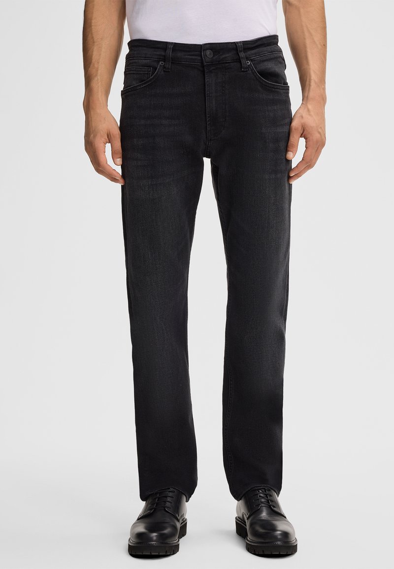 Jeans in denim nero con un taglio dritto, dotati di cinque tasche, chiusura con bottone e sfumature leggere per texture e stile. Abbinati a scarpe nere.