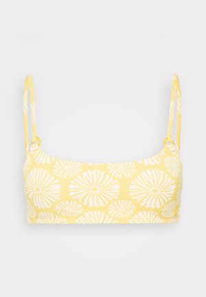 Żółty top bandeau z białym kwiatowym wzorem, z cienkimi ramiączkami i gładką teksturą. Prosty design, bez widocznych elementów ozdobnych czy sprzężenia.