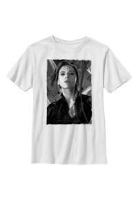 Vit bomulls t-shirt med en monokrom grafisk tryck av en kvinnas ansikte, med djärva penseldrag i bakgrunden.