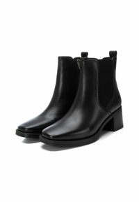 Stivali alla caviglia in pelle nera con una finitura liscia, pannelli laterali elasticizzati, tacco basso a blocco e punta affusolata. Chiusura con cerniera su un lato.