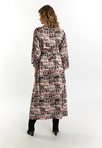 Rochie lungă, fluidă, cu un model abstract colorat în nuanțe de roșu, negru și crem. Are mâneci trei sferturi și un detaliu cu talie legată.