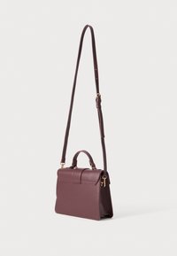 Sac à main en cuir bourgogne avec une forme structurée, une poignée supérieure et une bandoulière réglable. Il est doté d'accents en métal doré et d'une fermeture magnétique.