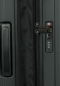 Valigia nera con un'esterno liscio e rigido, doppie cerniere, lucchetto approvato TSA e maniglia laterale per una facile impugnatura. Interno in tessuto testurizzato.