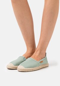 Grønne lerrets espadriller med en jute såle, med rund tå og liten sideetikett. Glatt finish med en lett tekstur.