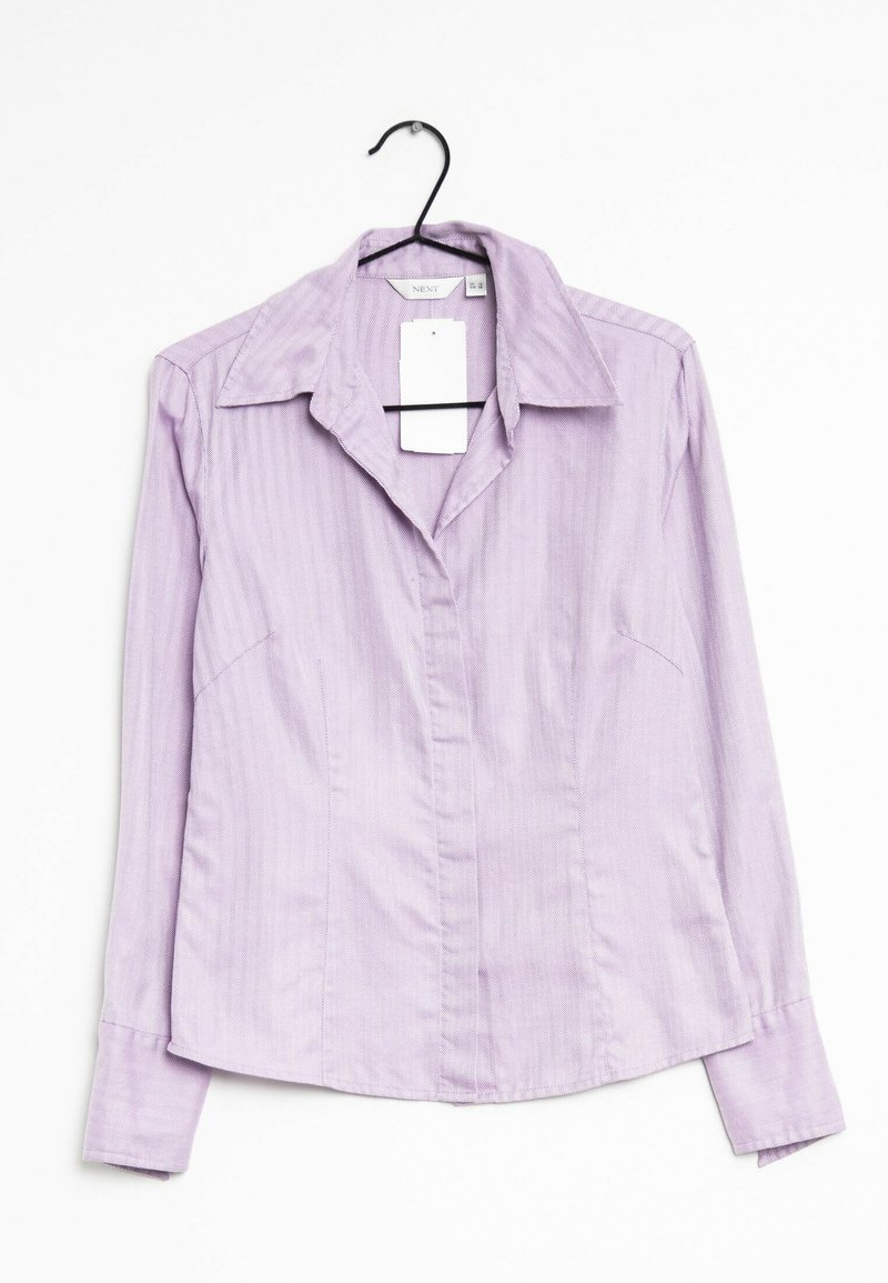 Chemise à manches longues de couleur violet clair avec un col, des rayures verticales subtiles et un devant à boutons. Accrochée à un crochet noir.