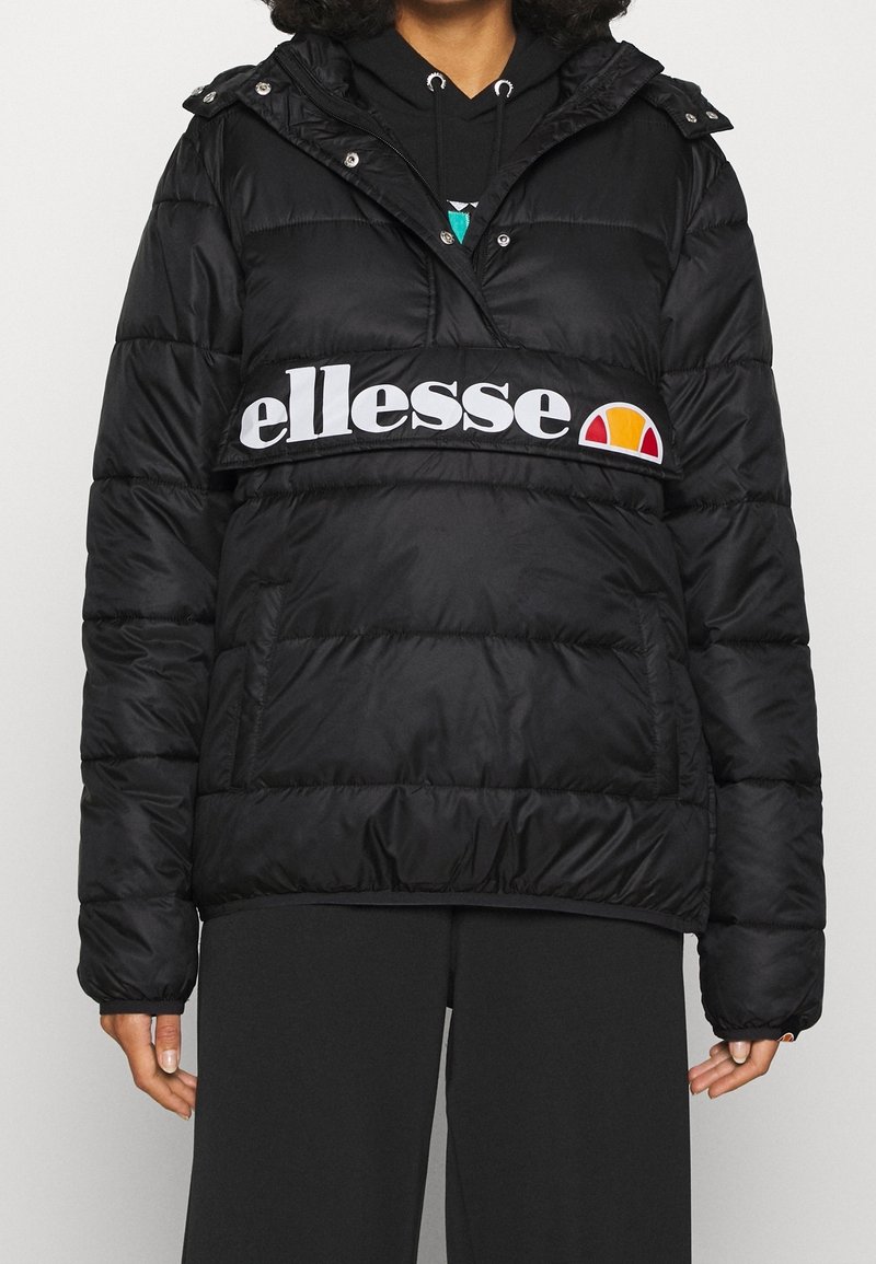 Chaqueta de plumas negra con capucha, que presenta una prominente banda de logotipo blanca en el pecho. Diseño texturizado y acolchado con bolsillos laterales.
