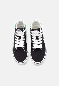 Ζευγάρι μαύρα ψηλά αθλητικά Vans με λευκά κορδόνια και πράσιν α μοτίβα, ορατά από πάνω σε λευκό φόντο.