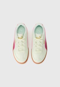 Hvite og rosa sneakers med en teksturert overflate, som har såle av gummi, snøring foran og en subtil gulllogo på siden.