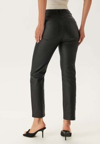 Zwarte, slim-fit broek van kunstleer, met standaardzakken, een gladde textuur en een rechte pijp.