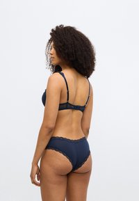 Σετ εσωρούχων σε ναυτικό μπλε με δαντέλα, που περιλαμβάνει σουτιέν με επένδυση και ρυθμιζόμενους ιμάντες και ταυτόχρονα σλιπ ψηλόμεσο, με περίτεχνη λεπτομέρεια.