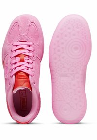 Sneakers in suede rosa con lacci coordinati, caratterizzati da una linguetta rossa a contrasto e suola in gomma rosa testurizzata con motivi circolari e loghi.