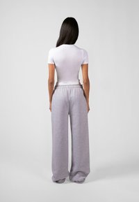 Hvitt kortermet tettsittende topp parret med lysegrå vide joggebukser med elastisk midje. Glatt stoff, avslappet passform.