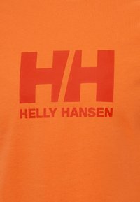 Oranžové bavlněné tričko s velkým červeným logem "HH" a textem "HELLY HANSEN" v kontrastní tučné červené barvě, hladká textura, kulatý výstřih.