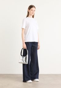 White short-sleeve t-shirt, dark denim wide-leg jeans, silver handbag with black handle, and white sneakers. Simple and casual design.