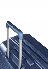 Harde koffer in marineblauw, met een textuurover oppervlak, zilveren uitschuifbare handgreep en een ritsvak met geïntegreerd greep paneel.