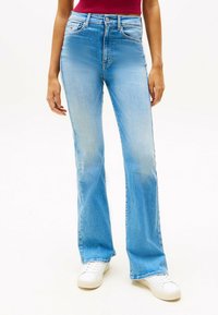 Vaqueros acampanados de talle alto en denim azul claro con un acabado desgastado, diseño de cinco bolsillos y cierre clásico de cremallera/botón.