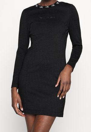 Slim-fit black dress with long sleeves, a branded "cK" logo pattern on the neckline, and subtle embossed text on the chest.