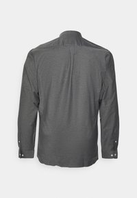 Camisa de manga larga gris oscuro con cuello tipo polo, puños abotonados y un pliegue en la parte posterior para mayor movilidad. Tejido suave y texturizado.
