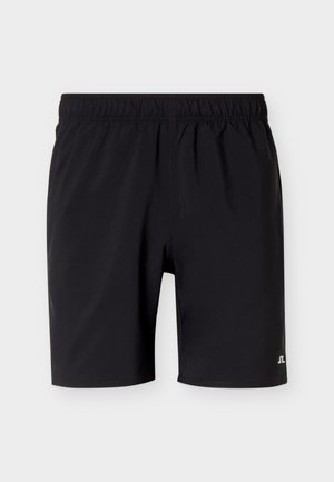 Μαύρα σορτς μέσης μήκους με ελαστική μέση και μικρό λευκό λογότυπο στο κάτω δεξί πόδι, απεικονίζεται σε απλό φωτεινό φόντο.