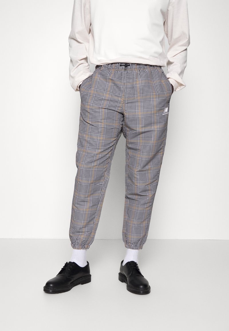 Checkered jogger pants in gray, black, and yellow with elastic waistband and ankle cuffs; paired with a light-colored long-sleeve shirt and black shoes.