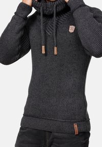 Pull tricot gris foncé avec un col haut, une texture côtelée et des accents à cordon. Comprend un petit patch logo sur la poitrine.