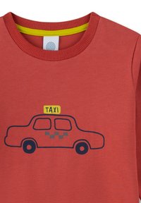 Roter Pullover mit einem blauen Taxi-Graphic, einem gelben Taxi-Schild und einem karierten Muster. Geripptes Halsband mit einem kontrastierenden gelben Akzent.