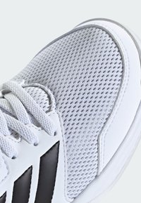 Biele športové topánky s priedušným sieťovaným vrchom, textúrovanými prekrytiami, čiernymi akcentmi a tradičným šnurovaním pre bezpečné uchytenie.