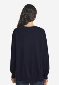 Marinefarbener, übergroßer Pullover mit geripptem Saum und Bündchen, ausgestattet mit einem klassischen Rundhalsausschnitt und weichem Strickmaterial, entworfen für eine lässige Passform.