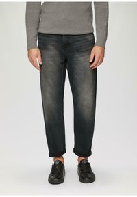 Donkerdenim jeans met een relaxte pasvorm, voorzien van een vervaagde textuur, omgeslagen mouwen en gestyled met zwarte sneakers.