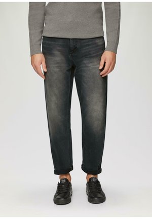 Donkerdenim jeans met een relaxte pasvorm, voorzien van een vervaagde textuur, omgeslagen mouwen en gestyled met zwarte sneakers.