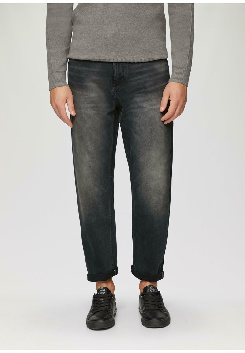 Donkerdenim jeans met een relaxte pasvorm, voorzien van een vervaagde textuur, omgeslagen mouwen en gestyled met zwarte sneakers.