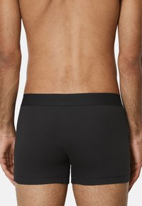Schwarze, enganliegende Boxershorts aus geripptem Stoff, mit einem glatten Bund und ohne Muster oder sichtbare Details auf der Rückseite.