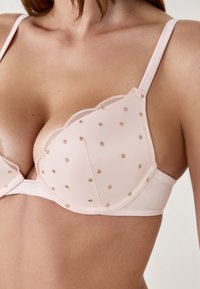 Reggiseno rosa con bordi in pizzo scallop e motivo a pois. Materiale morbido con spalline regolabili e supporto con ferretto.