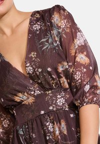 Blumenkleid in dunklem Burgunderrot, aus leichtem Material. Verfügt über einen tiefen V-Ausschnitt, Puffärmel und einen gerafften Taillenbereich, geschmückt mit hellen Blumenmustern.