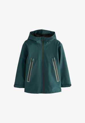 Tengerkék vízálló dzseki kapucnival, elöl zipzárral és két zipzáras zsebbel, geometrikus díszítésekkel. Simaság jellemzi.