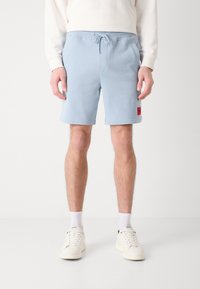 Shorts din bumbac de culoare albastru deschis, cu un elastic în talie, dotate cu un cordon de ajustare și buzunare laterale. Prezintă o mică etichetă roșie cu logo.
