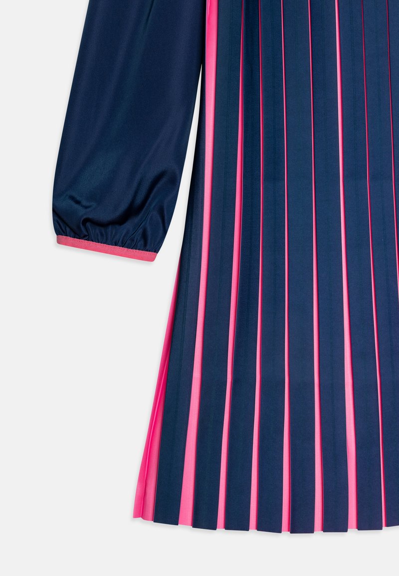 Sotilasmainen sininen mekko, jossa on röyhelöitä vaaleanpunaisten yksityiskohtien kanssa, pitkät ilmapallohihat ja vaaleanpunainen reunus hihojen reunoissa ja röyhelöissä.