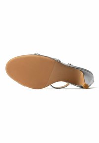 Silberne offene High-Heel-Sandale mit offenem Zehenbereich, von unten gezeigt, mit einer strukturierten braunen Sohle und einer schlanken Absatzspitze.