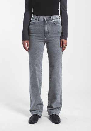 High-waisted, light gray jeans with a straight leg design, made of denim. Features front pockets and a button closure. Worn with black footwear.